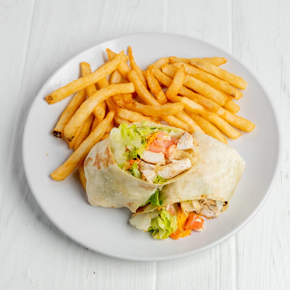 Chicken and vegetable wrap served with golden French fries on a white plate.